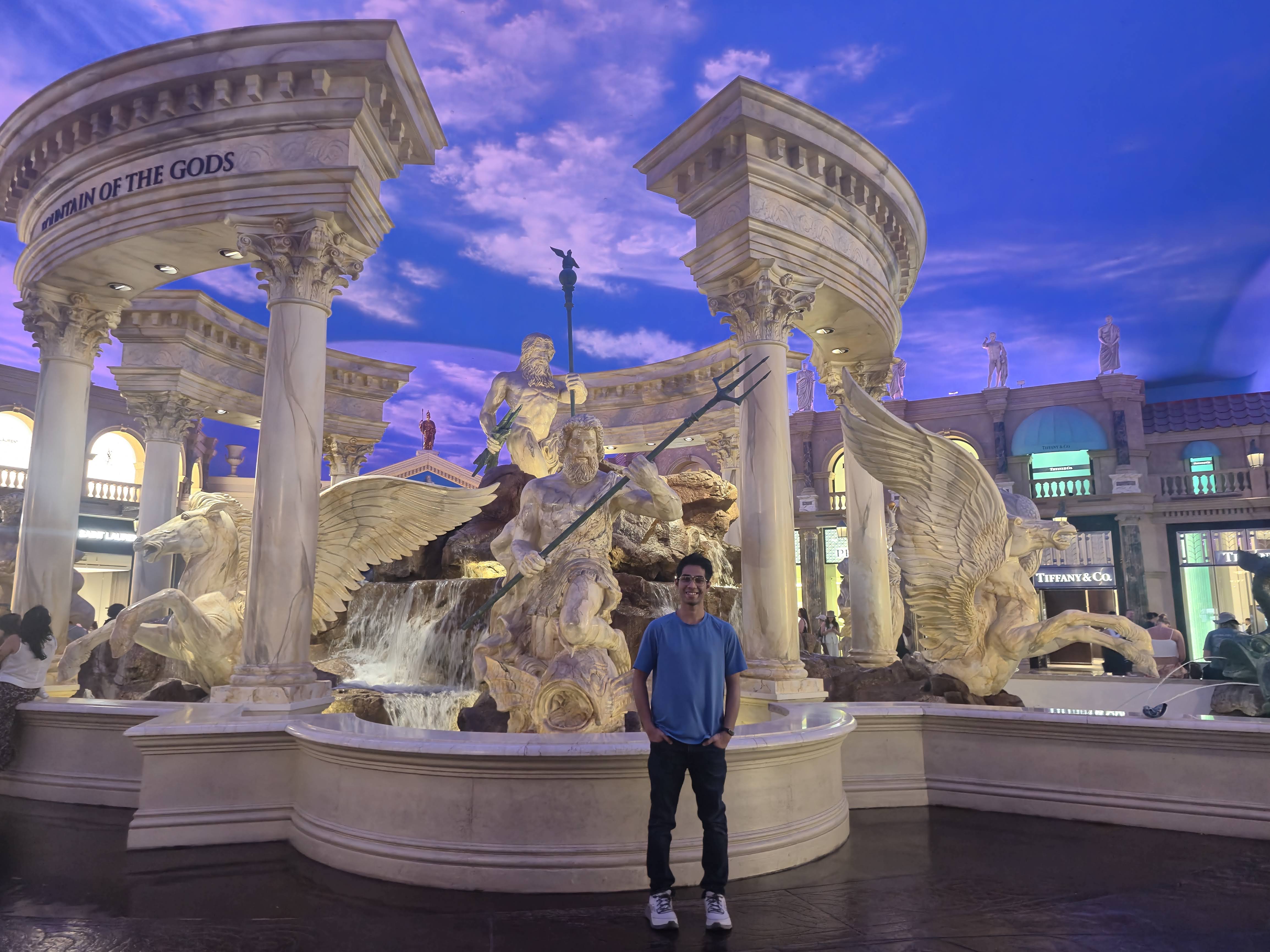 Aldrin standing in front of the ornate marble 'Fountain of the Gods' inside Caesars Palace, beneath a painted blue-sky ceiling