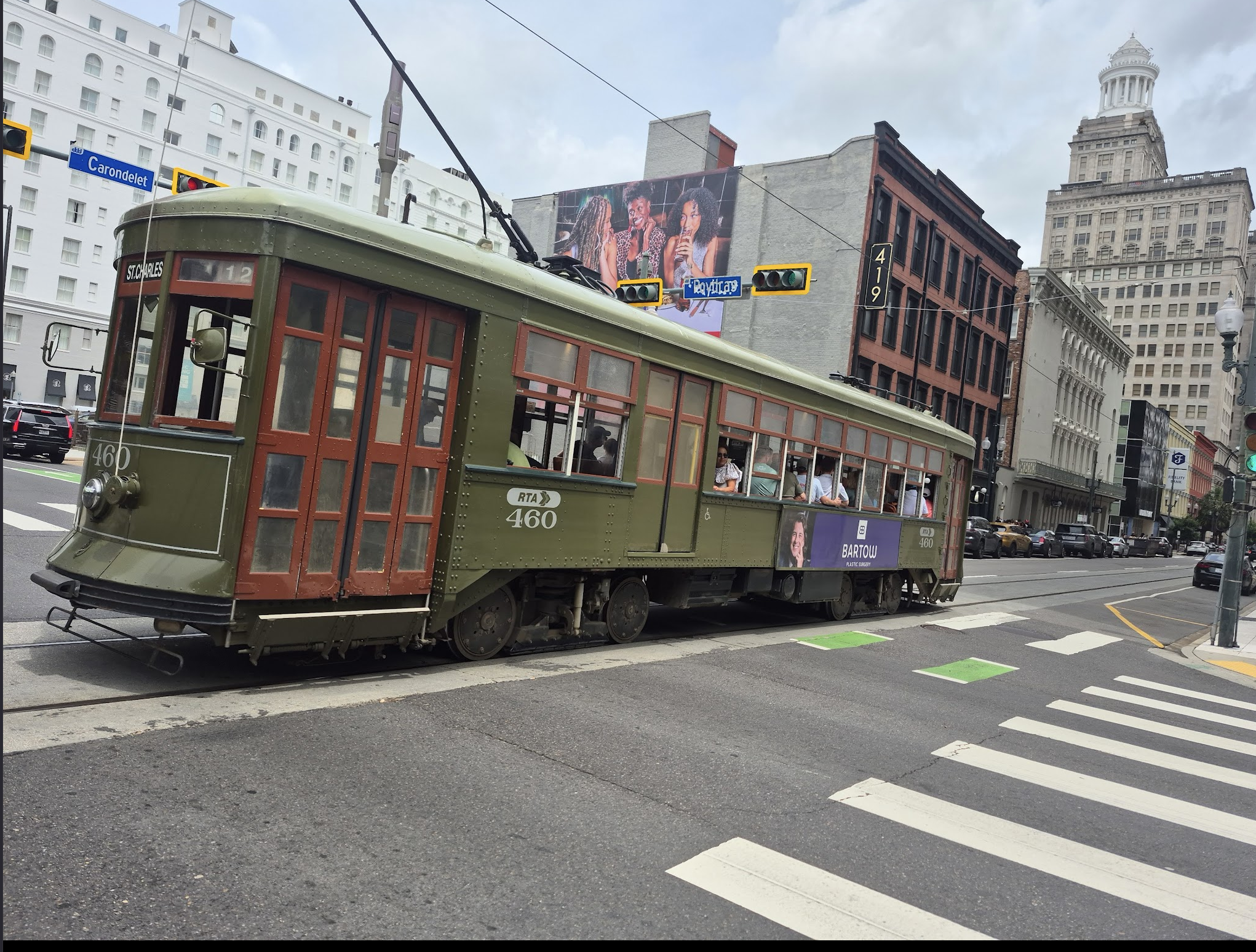 The historic olive-green St. Charles Avenue streetcar, car number 460, crossing an intersection in downtown New Orleans